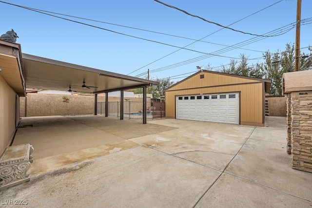 detached garage with fence and a ceiling fan