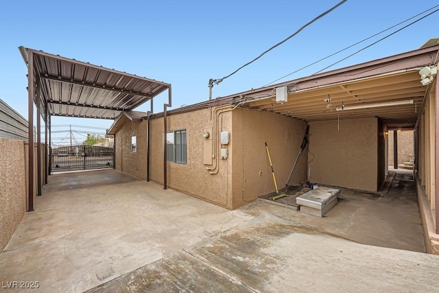 view of patio with a carport, a gate, fence, and driveway