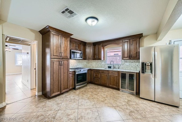 kitchen with tasteful backsplash, wine cooler, stainless steel appliances, and a sink