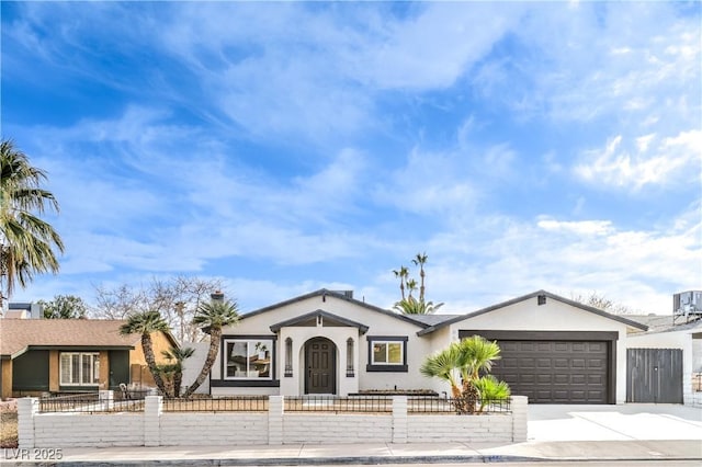 view of front of home featuring an attached garage, a fenced front yard, concrete driveway, and stucco siding