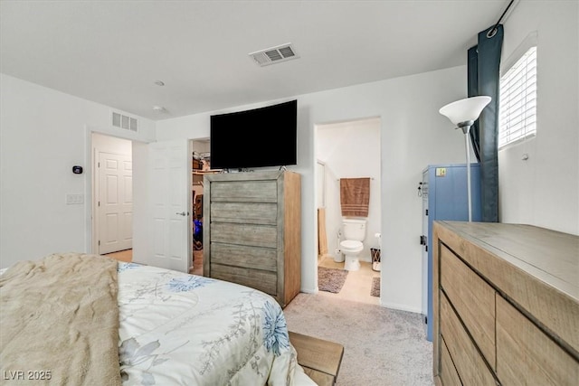 bedroom with light carpet, visible vents, a walk in closet, and a closet