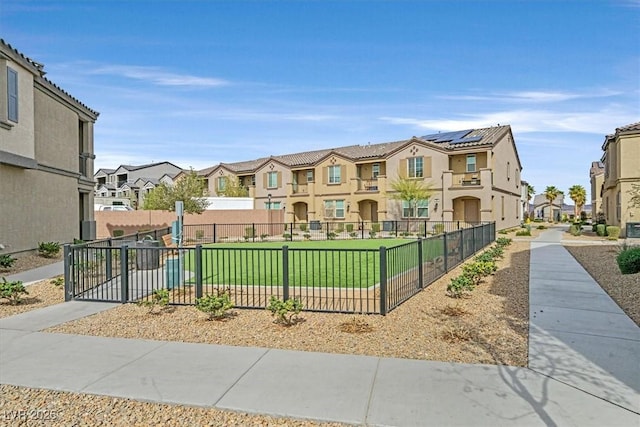 view of front of property with a tile roof, stucco siding, a front yard, fence, and a residential view