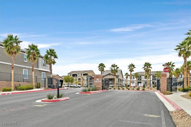 view of street with a gate, a gated entry, sidewalks, and a residential view