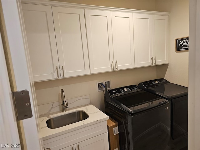 laundry room with cabinet space, washer and dryer, and a sink