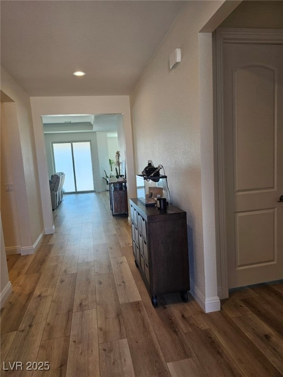 hall with light wood-style floors, baseboards, and recessed lighting