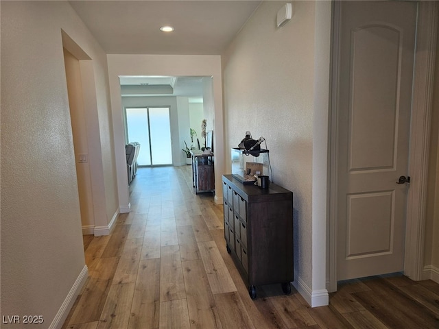 hall featuring light wood-style floors and baseboards