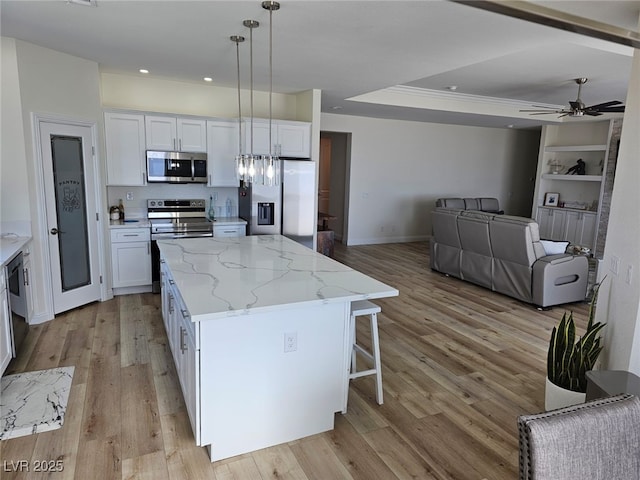 kitchen with light wood-style flooring, white cabinetry, stainless steel appliances, and a raised ceiling