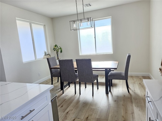 dining area with baseboards, visible vents, light wood finished floors, and an inviting chandelier