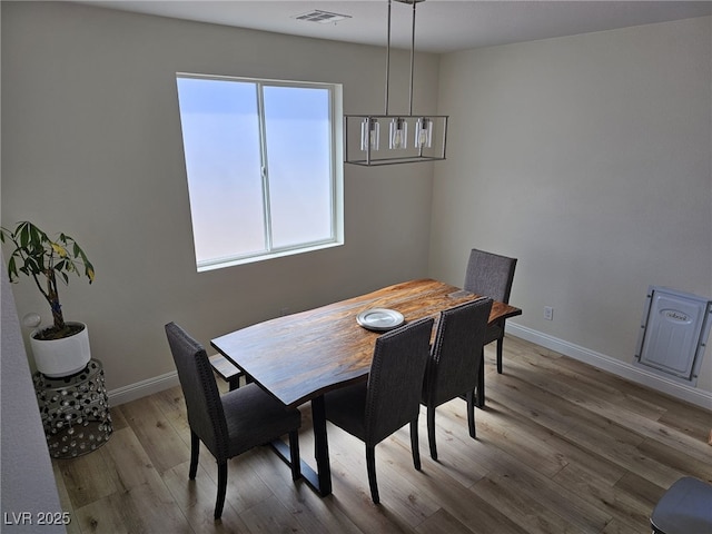 dining area with wood finished floors, visible vents, and baseboards