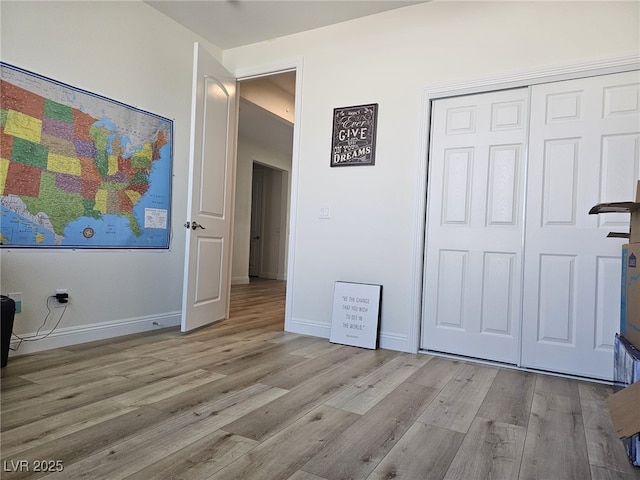 unfurnished bedroom with a closet, baseboards, and wood finished floors