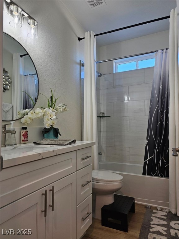 full bathroom featuring toilet, wood finished floors, vanity, and shower / tub combo with curtain