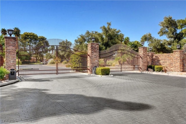 view of road featuring street lighting, a gate, curbs, and a gated entry