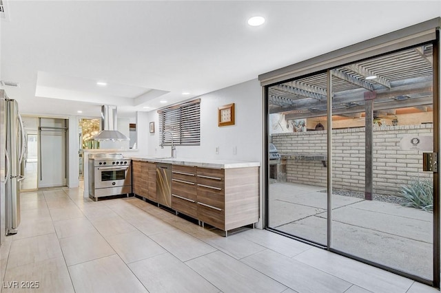 kitchen with a sink, light countertops, appliances with stainless steel finishes, range hood, and modern cabinets