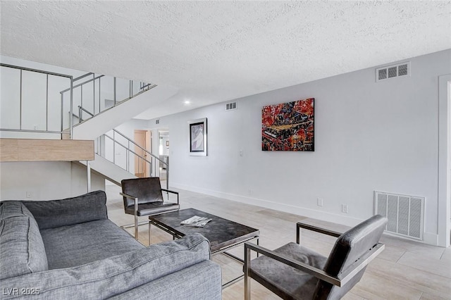 living area featuring visible vents, baseboards, and stairs