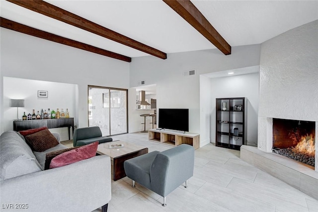 living room featuring vaulted ceiling with beams, a large fireplace, visible vents, and a bar