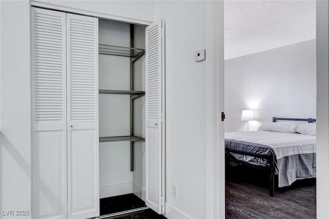 interior space featuring dark wood-style floors, baseboards, and a closet