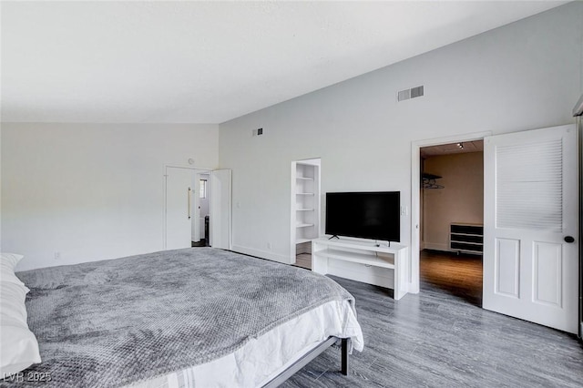 bedroom featuring lofted ceiling, visible vents, baseboards, and wood finished floors