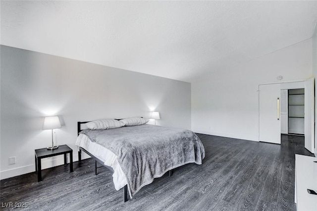 bedroom with dark wood-style flooring, vaulted ceiling, and baseboards