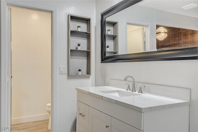 bathroom with toilet, baseboards, wood finished floors, and vanity