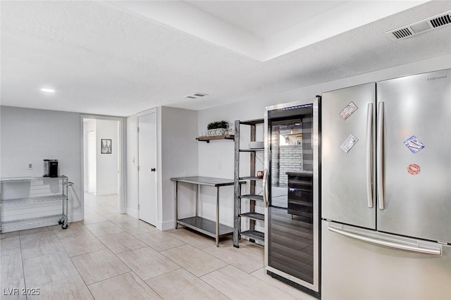 kitchen with baseboards, visible vents, a textured ceiling, and freestanding refrigerator