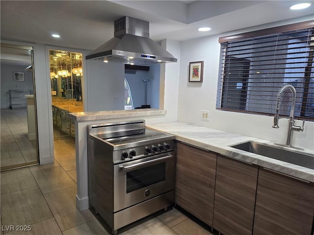 kitchen featuring recessed lighting, high end stainless steel range oven, a sink, wall chimney range hood, and tile patterned floors