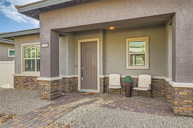 property entrance with stone siding, a patio, and stucco siding