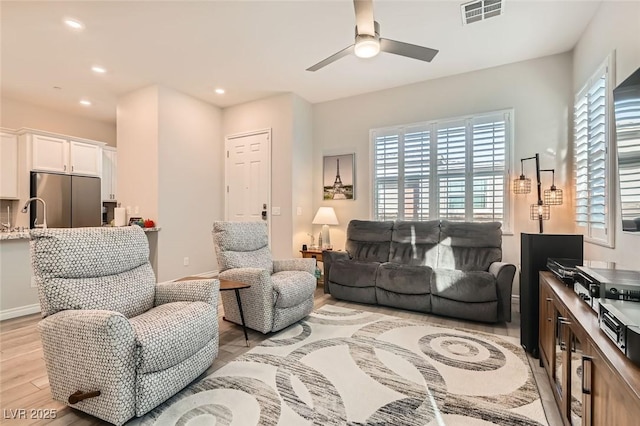 living room featuring baseboards, visible vents, a ceiling fan, light wood-type flooring, and recessed lighting