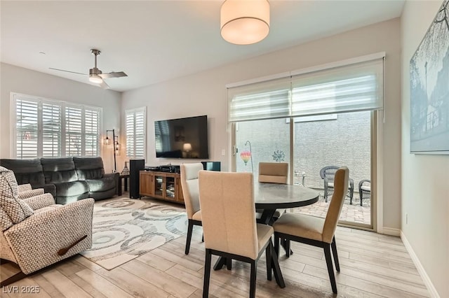 dining area featuring a ceiling fan, light wood-style flooring, and baseboards