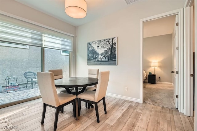 dining space featuring light wood finished floors, visible vents, and baseboards