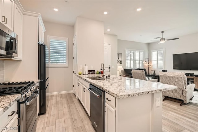 kitchen with a peninsula, appliances with stainless steel finishes, a sink, and white cabinetry