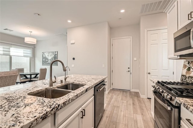 kitchen with visible vents, white cabinets, stainless steel appliances, light wood-style floors, and a sink