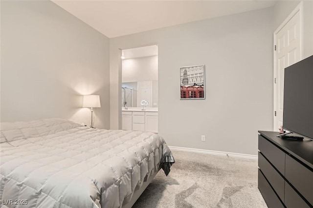 carpeted bedroom with ensuite bathroom and baseboards