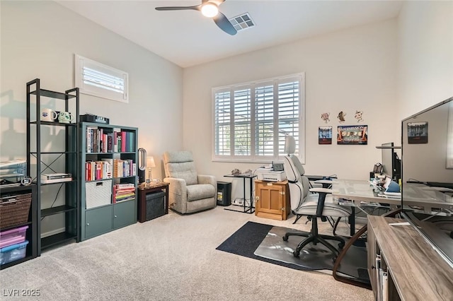 office area featuring a wealth of natural light, a ceiling fan, visible vents, and light colored carpet