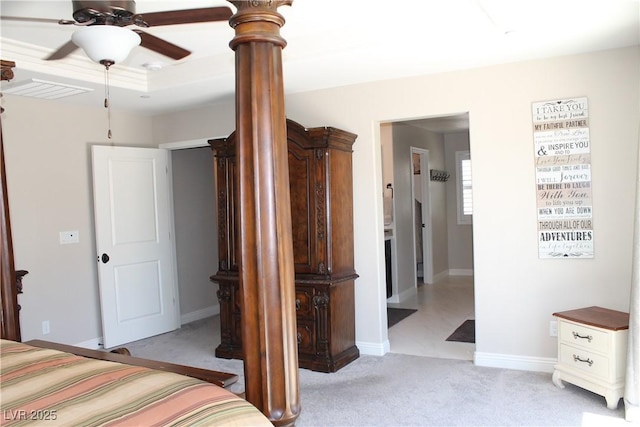 bedroom featuring light carpet, baseboards, visible vents, and a tray ceiling