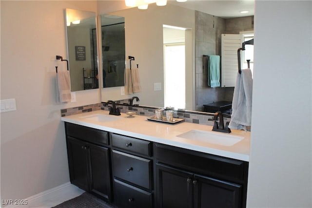 full bath with double vanity, baseboards, backsplash, and a sink