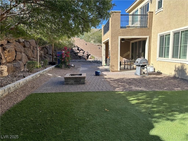 view of yard with a balcony, an outdoor fire pit, fence, and a patio