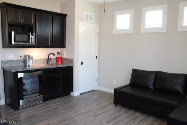 interior space featuring beverage cooler, light wood-style flooring, visible vents, and baseboards