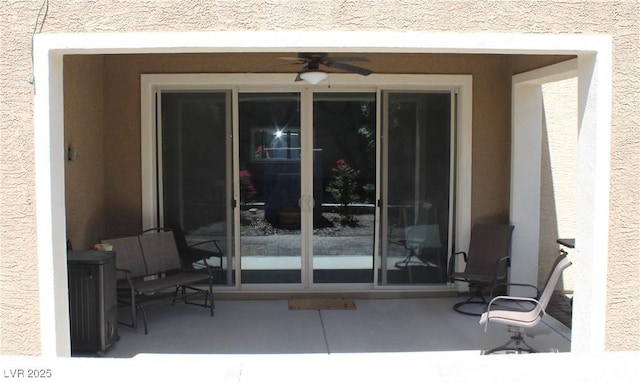 property entrance featuring a patio, a ceiling fan, and stucco siding