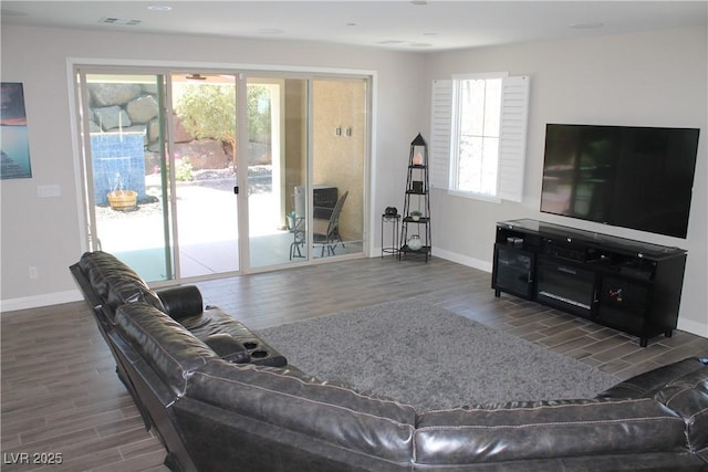 living area with wood finish floors, visible vents, and a healthy amount of sunlight