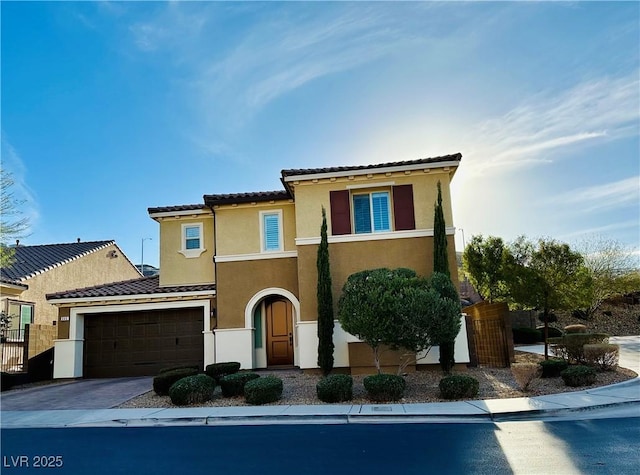 view of front of house with driveway, a garage, a tile roof, fence, and stucco siding