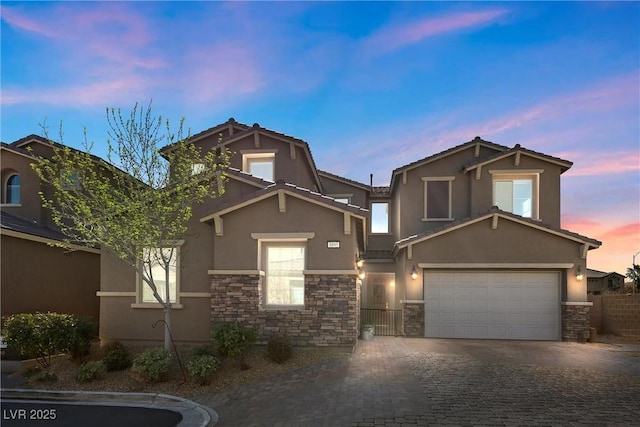 view of front of home with a garage, stone siding, decorative driveway, and stucco siding