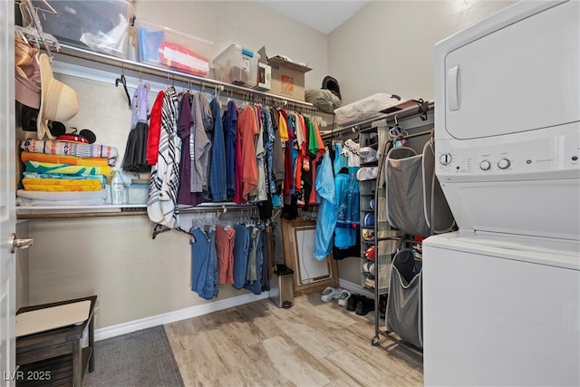 walk in closet with wood finished floors and stacked washer / drying machine