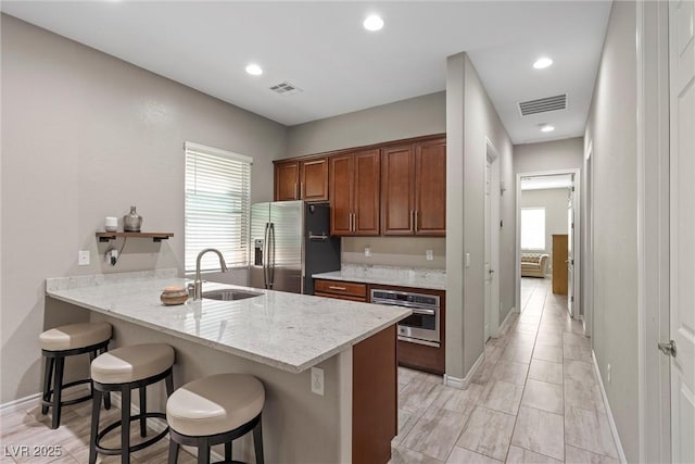 kitchen featuring a kitchen bar, visible vents, stainless steel appliances, and a sink