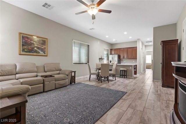 living area featuring baseboards, plenty of natural light, visible vents, and a ceiling fan