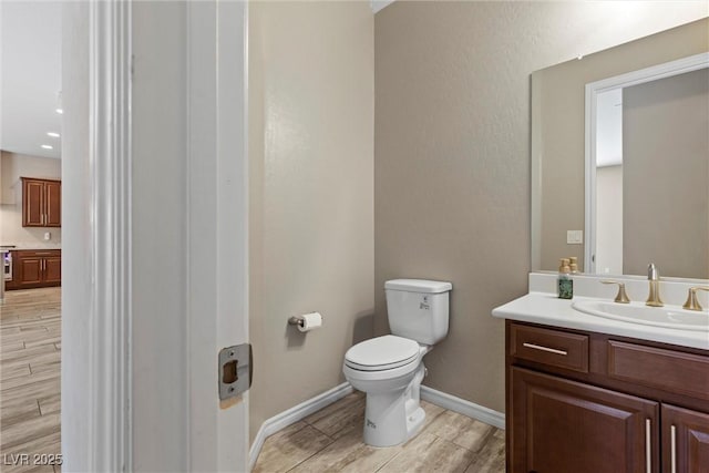 bathroom with toilet, wood tiled floor, baseboards, and vanity