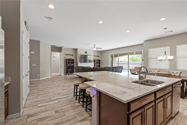 kitchen featuring visible vents, a breakfast bar area, open floor plan, a kitchen island with sink, and a sink