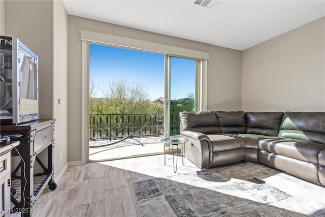 living room with light wood finished floors, baseboards, and visible vents