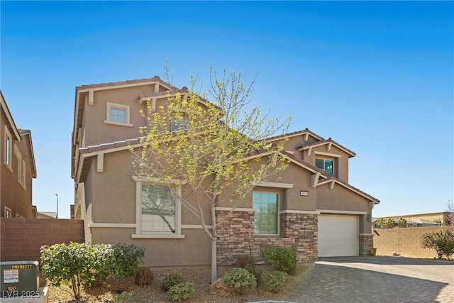 craftsman inspired home featuring stone siding, fence, decorative driveway, and stucco siding