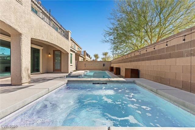 view of swimming pool with a fenced backyard and an in ground hot tub