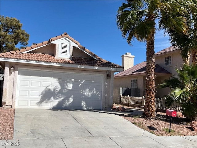 view of front of property featuring a tiled roof, fence, driveway, and stucco siding